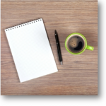 notepad, pen and a cup of coffee on a desktop